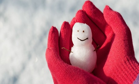 small snowman in hands wearing red gloves